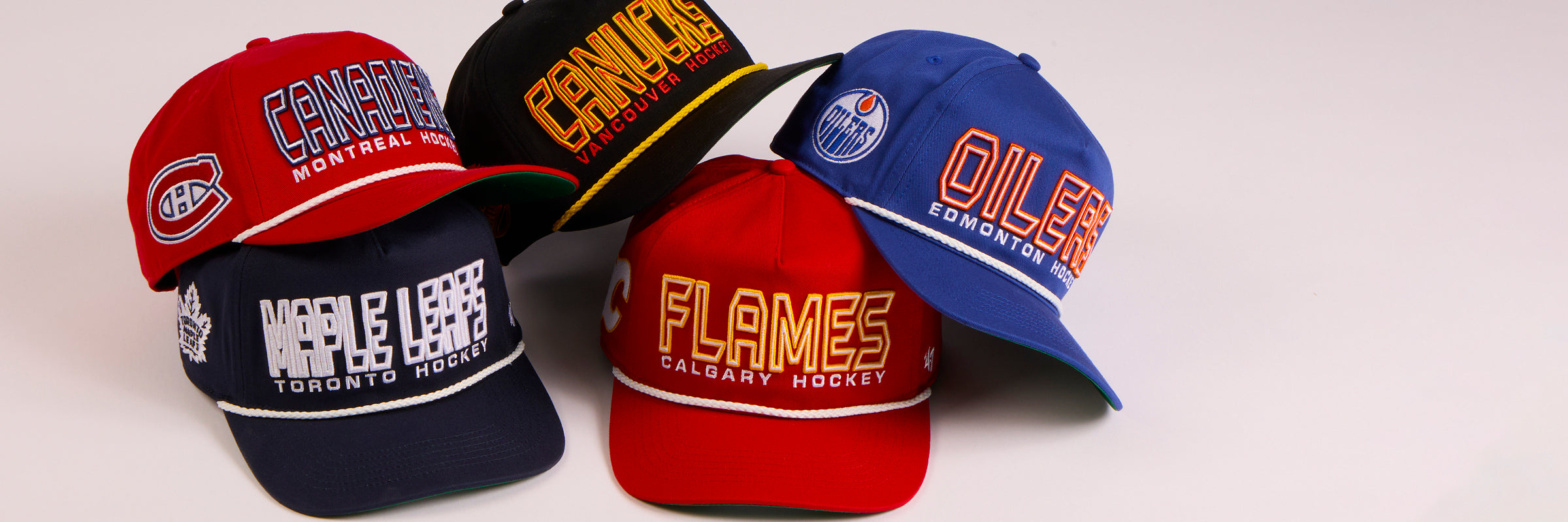 Five hockey team caps from different teams on a white background